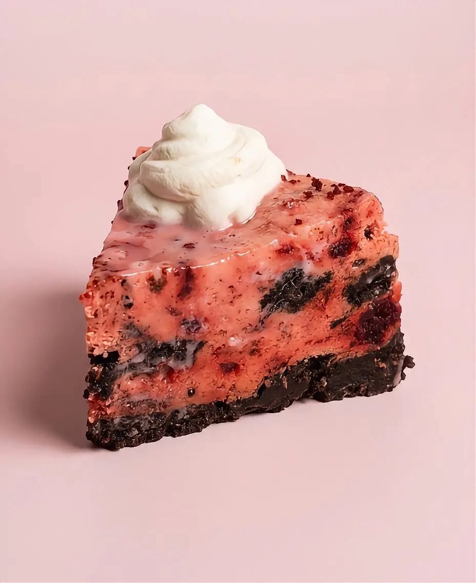 Slice of Red Velvet Cookies & Cream cheesecake with chocolate chunks and a cream swirl